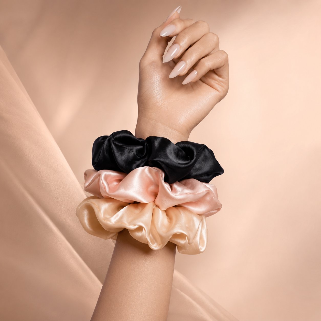 Three anielenia silk scrunchies in black, blush, and champagne