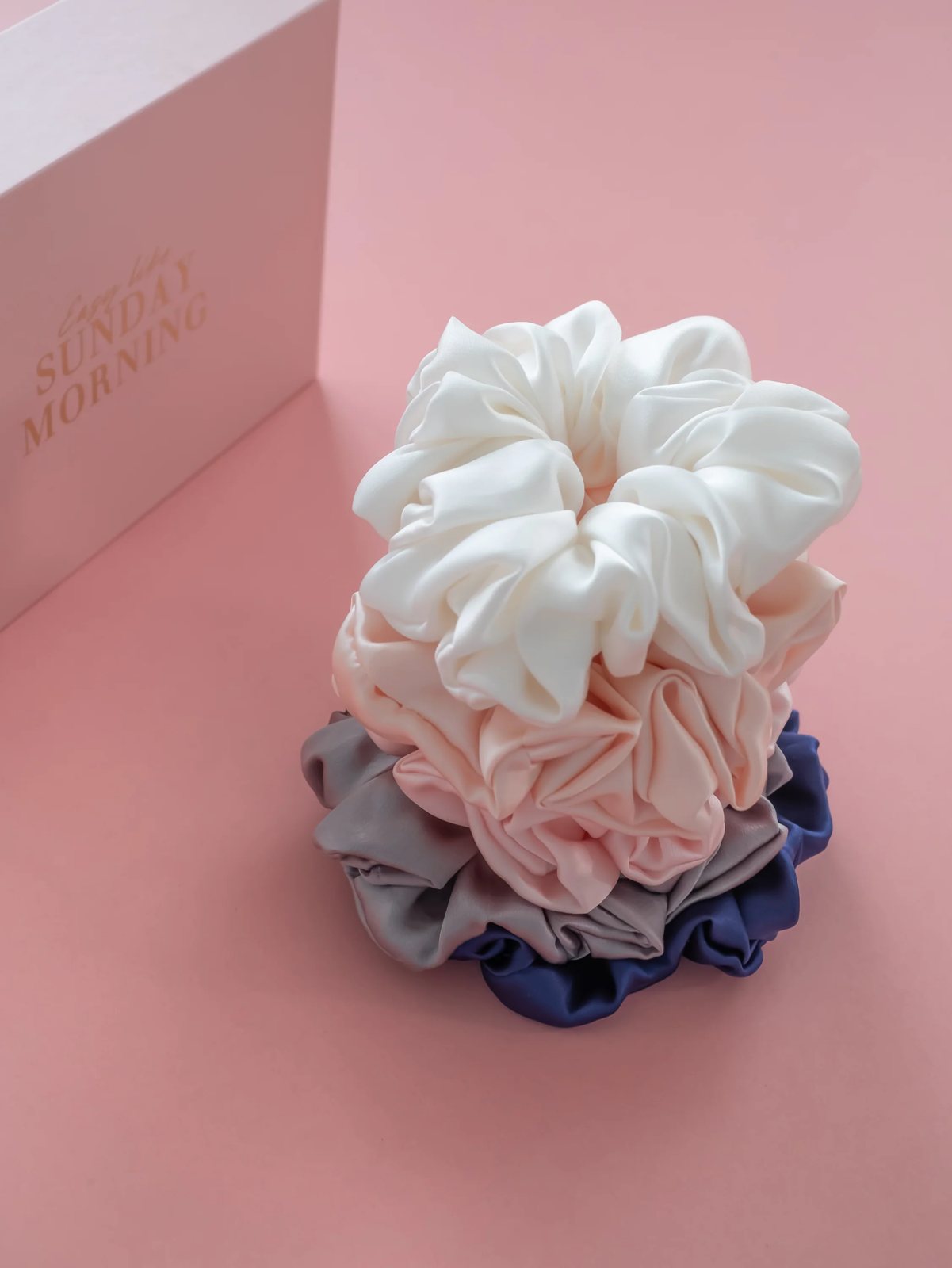 A stack of anielenia silk scrunchies in soft everyday shades